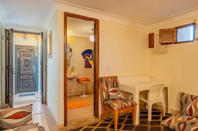 a room with a table and a chair and a bathroom at Maison Du Tresor in Marrakech