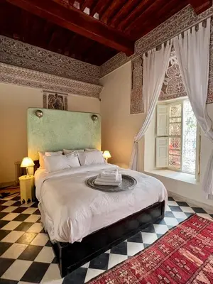a bedroom with a large bed and a checkered floor at Riad Tizwa Marrakech in Marrakech