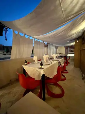a row of tables with red chairs under a white tent at Riad Tizwa Marrakech in Marrakech