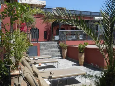 a row of tables and benches in front of a building at Riad Alegria in Marrakech