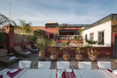 an outdoor patio with chairs and tables and plants at Riad Alegria in Marrakech