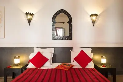 a bedroom with a bed with red pillows and a mirror at Riad Alegria in Marrakech