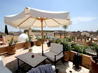 a patio with an umbrella and a table on a roof at Riad Lyla in Marrakech