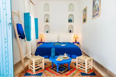 a bedroom with a blue bed and two chairs at Riad Chamali in Marrakech