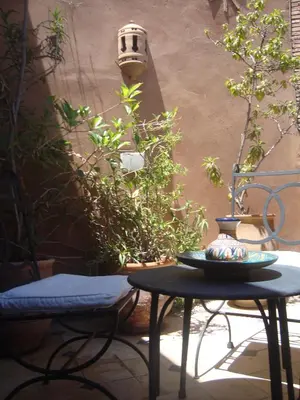 a table with a vase on it next to some plants at Riad Jnane Mogador in Marrakech