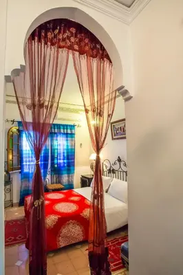 a bedroom with a red bed with curtains at Riad Jnane Mogador in Marrakech