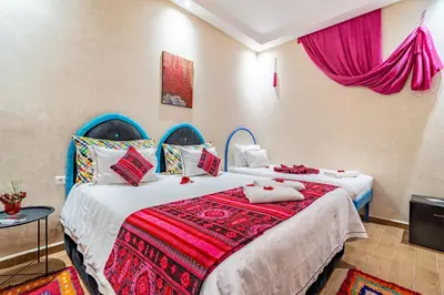 two beds in a room with pink curtains at Maison KA in Marrakech