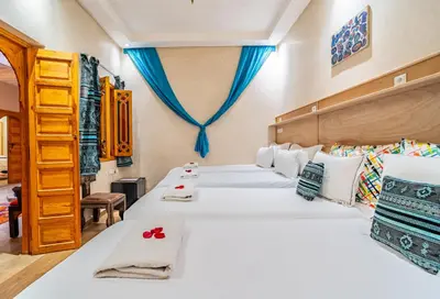 two beds in a room with blue curtains at Maison KA in Marrakech