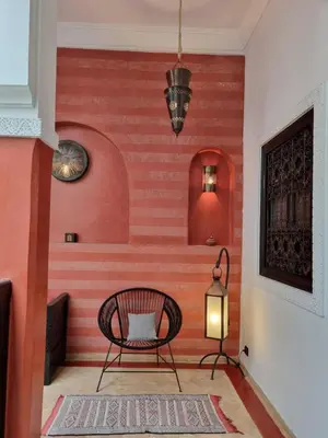 a chair in a room with a red wall at Riad les Rêves d'Amélie in Marrakech