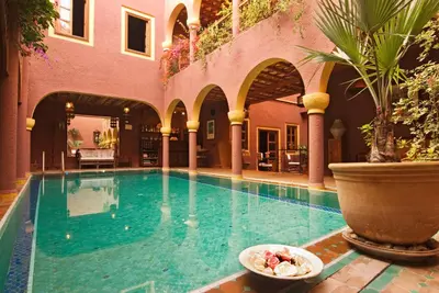 a swimming pool with a bowl of food next to a building at Riad Noga in Marrakech
