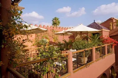 a balcony with plants and an umbrella at Riad Noga in Marrakech