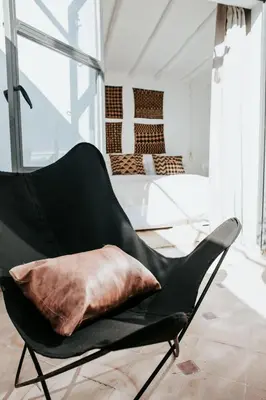 a black chair with a pillow in a bedroom at Dar Titrit in Marrakech
