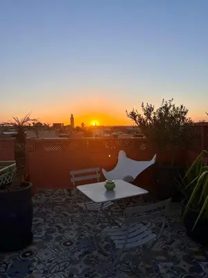 a table and chairs on a balcony with the sunset at Ryad El Borj in Marrakech