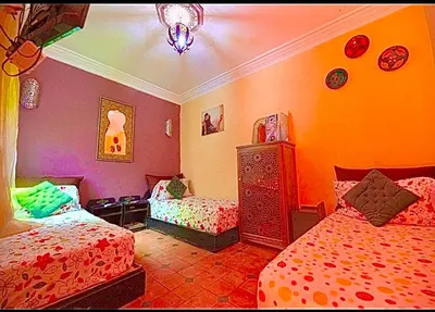 a bedroom with two beds and a chandelier at Riad Maison Aicha in Marrakech