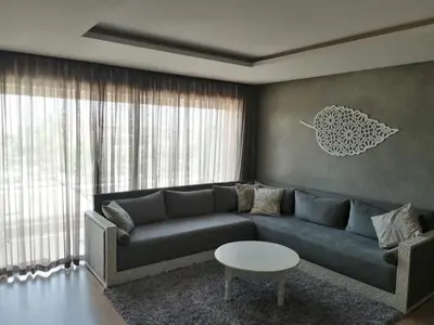 a living room with a blue couch and a table at Prestigia Marrakech Village Appartment in Marrakech
