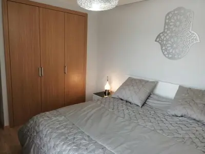 a bedroom with a bed and a wooden cabinet at Prestigia Marrakech Village Appartment in Marrakech