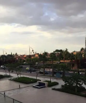 a park with a bench in a parking lot at Prestigia Marrakech Village Appartment in Marrakech