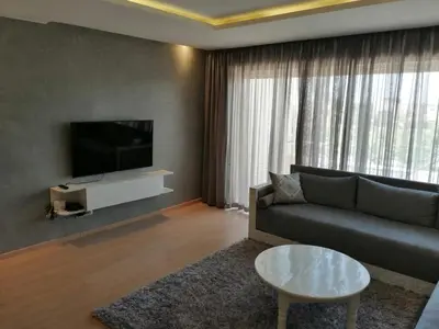 a living room with a couch and a tv at Prestigia Marrakech Village Appartment in Marrakech