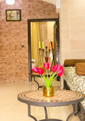a table with red flowers on it in a room at Miramare Marrakech in Marrakech