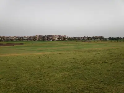 a green golf course with buildings in the background at Magnifique appart vue sur golf in Marrakech