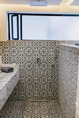 a bathroom with a tub and a tile wall at Riad Aïcha Kitchen in Marrakech