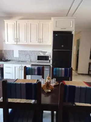 a kitchen with a table with chairs and a black refrigerator at Stylish Moroccan Apartment Gueliz City Centre in Marrakech