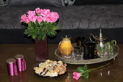 a table with a vase of flowers and a tray of food at Riad Terra Bahia in Marrakech
