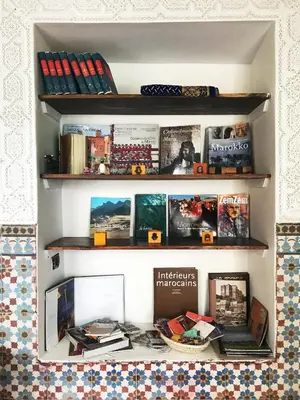 a shelf with books and a desk with books at Riad Orange in Marrakech