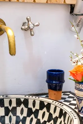 a sink with a blue cup next to a faucet at Riad Bobby Marrakech in Marrakech