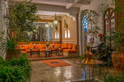 a living room with orange couches and plants at Riad Sable Chaud in Marrakech