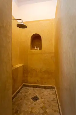 a bathroom with a shower with a yellow wall at Riad Ambre et Jasmin in Marrakech