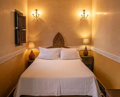 a bedroom with a white bed with two lights on the wall at Riad Bab Chems in Marrakech