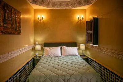 a bedroom with a bed with two lights on the wall at Riad Bab Chems in Marrakech