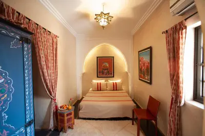 a bedroom with a bed and a chandelier at Riad des trois palais in Marrakech