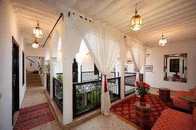 a hallway with a balcony with white curtains at Riad des trois palais in Marrakech
