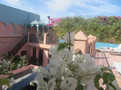 a view of a house with white flowers in the foreground at Riad Marélia in Marrakech