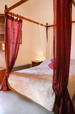 a bedroom with a canopy bed with red curtains at Riad Marélia in Marrakech