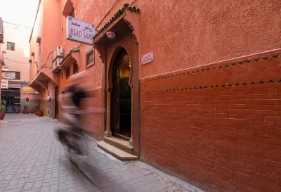 a person walking down a street next to a brick building at Riad Saad in Marrakech