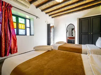 two beds in a room with two windows at Kasbah Alili in Marrakech
