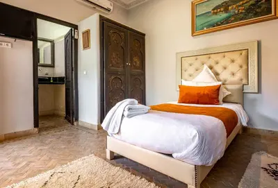 a bedroom with a large bed with orange and white sheets at Kasbah Alili in Marrakech