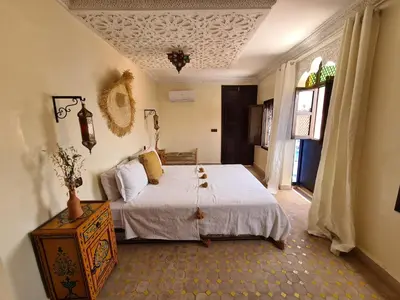 a bedroom with a bed and a table and a window at Riad Casa Sophia in Marrakech