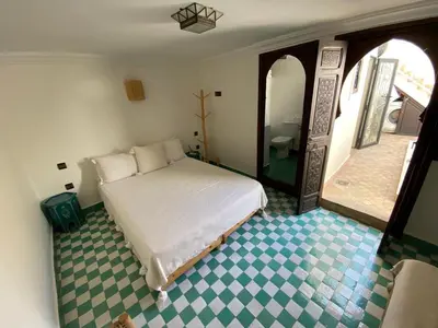 a bedroom with a white bed and a bathroom at Riad Casa Sophia in Marrakech