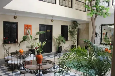 a courtyard with tables and chairs and plants at Riad Le Bel Oranger in Marrakech