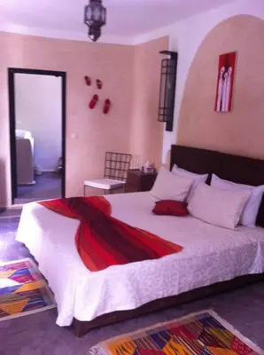 a bedroom with a large bed with a red blanket at Riad Le Bel Oranger in Marrakech