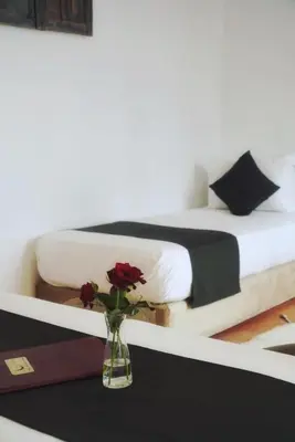 a vase with flowers on a table with a bed at Riad Twilight in Marrakech