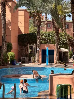 a group of people in a swimming pool with palm trees at Riad Hicham in Marrakech in Marrakech