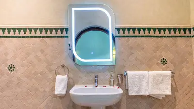 a bathroom with a sink and a mirror and towels at Riad Bab Tilila in Marrakech