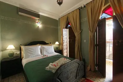 a bedroom with a bed with green walls and a window at Riad Bab Tilila in Marrakech