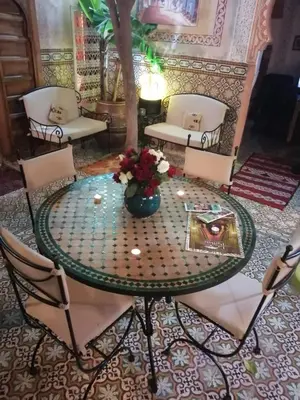 a table and chairs with a vase of flowers on it at RIAD Redous in Marrakech