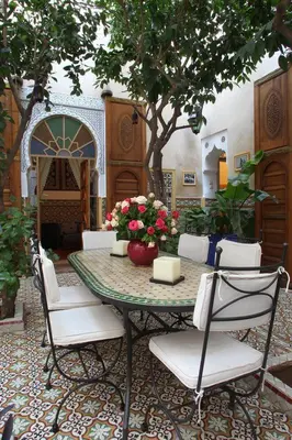 a table with white chairs and flowers on it at RIAD Redous in Marrakech